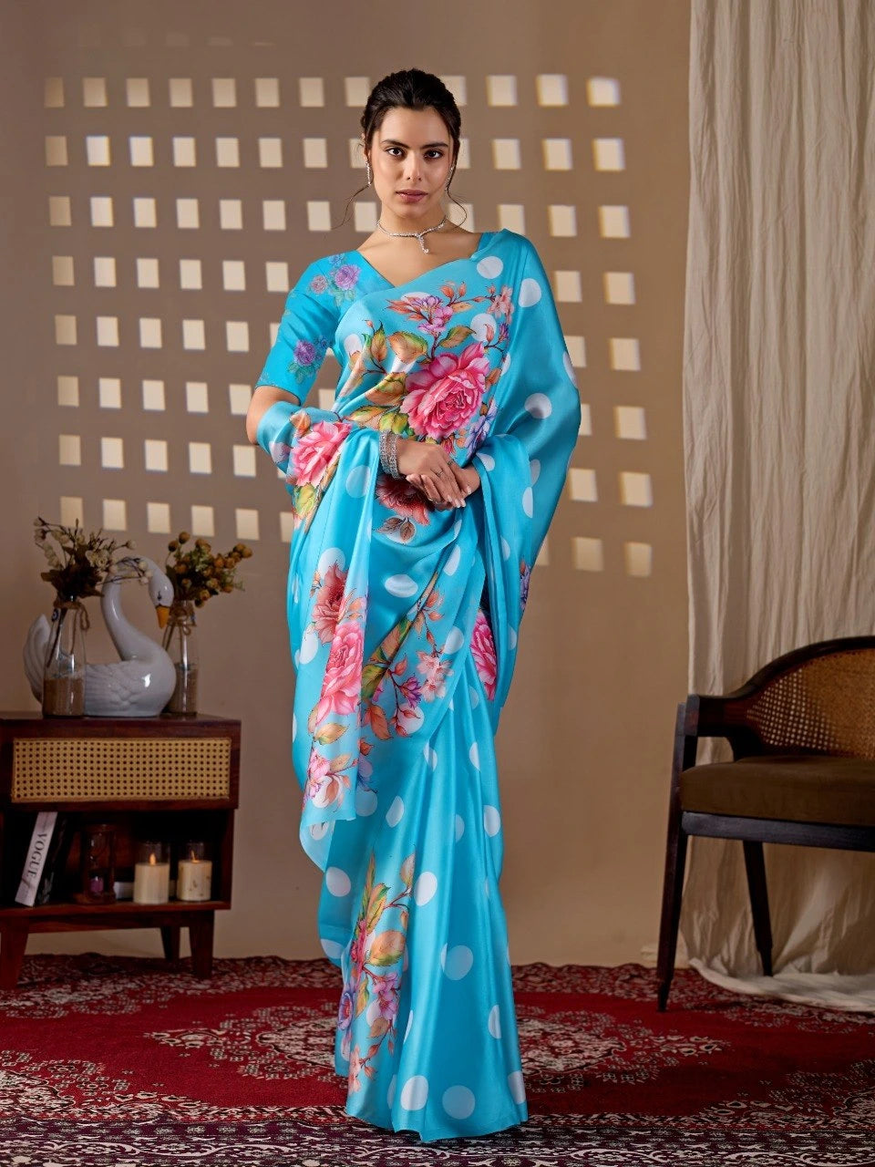 Woman wearing a blue saree with floral patterns in a room setting.